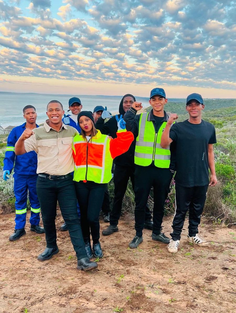 The NJ Services crew together on a dune above the sea at sunset